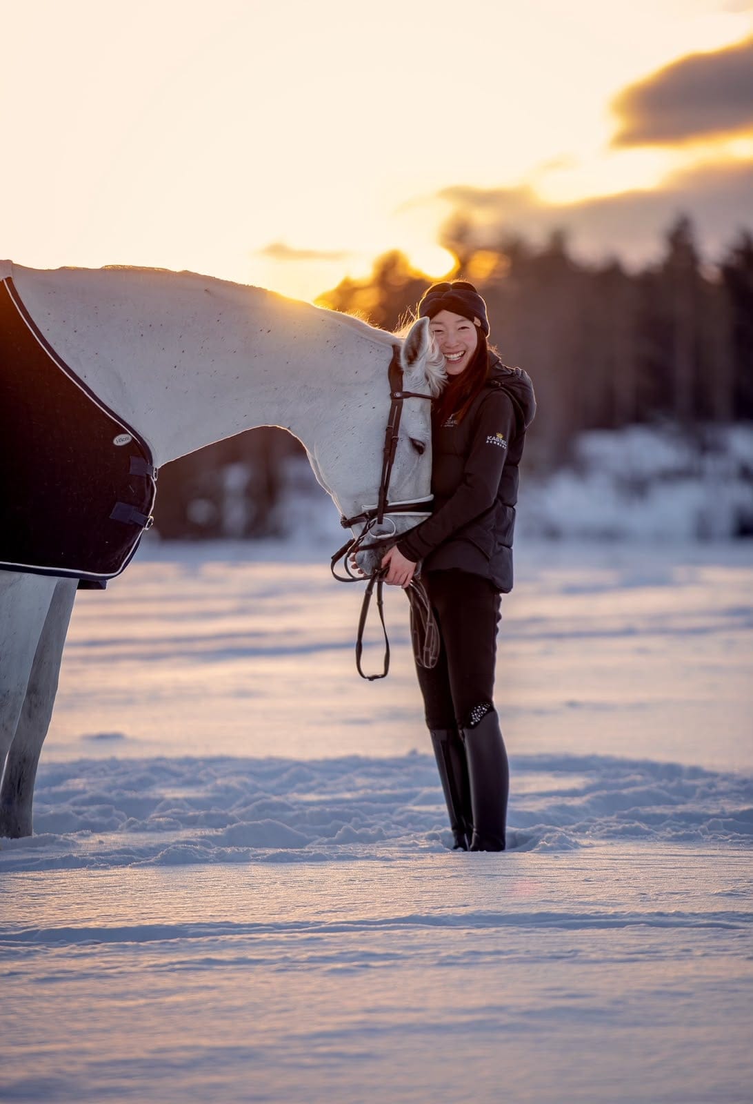 Yuka and a grey horse at golden hour in the snow